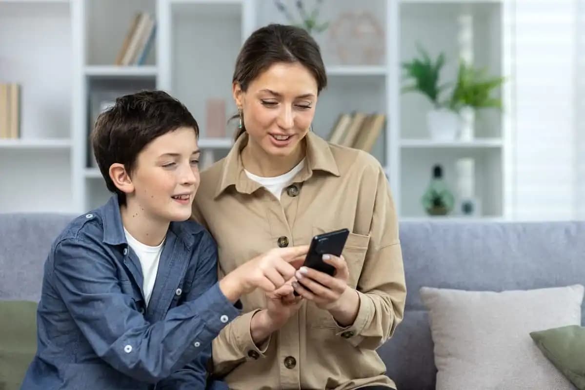 Une maman montrant quelque chose à son fils sur son téléphone, tout deux heureux