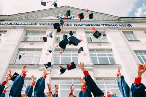 étudiant qui lancent leur chapeau de diplômé en l'air